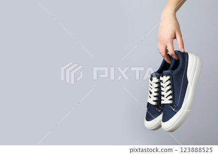 Stylish sneakers in hand on a light background Stylish sneakers in hand on a light background 123888525