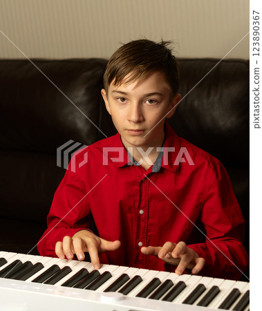 Teen boy playing piano, fingers pressing the keys. Teen boy playing piano, fingers pressing the keys. 123890367