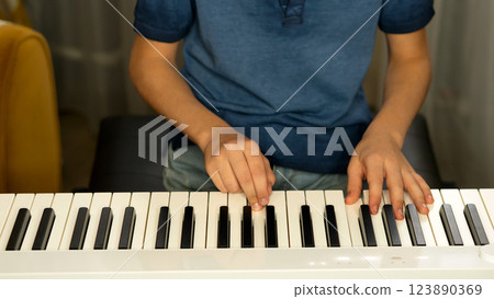 Child practicing finger placement on digital piano indoors 123890369
