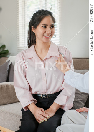A woman in a pink shirt smiles during a medical checkup at home, highlighting healthcare and wellness in a comfortable setting. A woman in a pink shirt smiles during a medical checkup at home, highlighting healthcare and wellness in a comfortable setting. 123890957