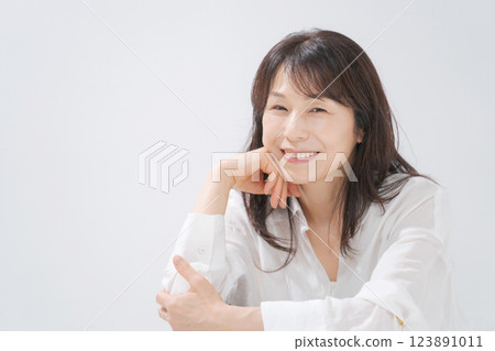 A woman in her 50s sitting with a smile A woman in her 50s sitting with a smile 123891011