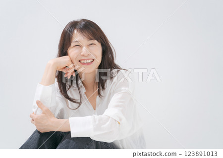 A woman in her 50s sitting with a smile A woman in her 50s sitting with a smile 123891013