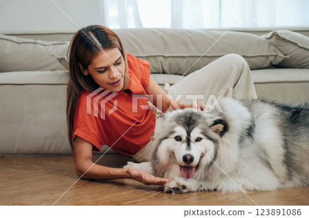 woman is petting a dog on the floor woman is petting a dog on the floor 123891086