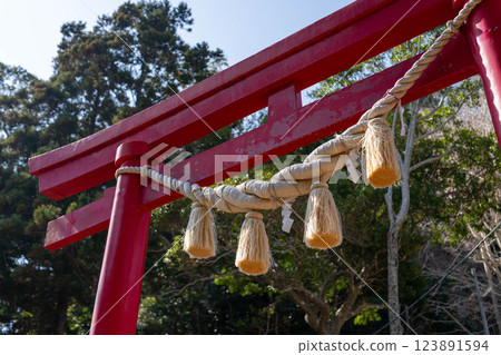 Vermilion torii gate and sacred rope standing out against the blue sky 123891594