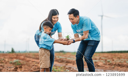 family of three, a man, a woman and a child, are planting a tree together 123891699