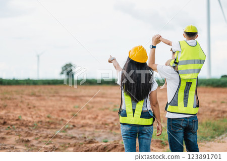 family of three, a man and two women, are standing in a field 123891701