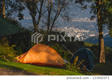 landscape and travel concept with camping tent on mountain and city background landscape and travel concept with camping tent on mountain and city background 123892071