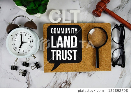 CLT - Community Land Trust acronym with alarm clock and magnifying glass, communication concept background CLT - Community Land Trust acronym with alarm clock and magnifying glass, communication concept background 123892798