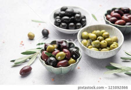 Assorted olives in decorative bowls on white surface 123892866