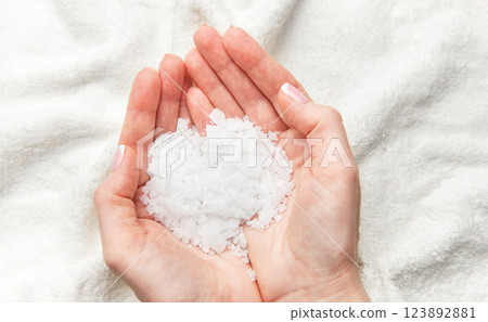 Woman holding white magnesium chloride flakes in hands for a relaxing bath Woman holding white magnesium chloride flakes in hands for a relaxing bath 123892881