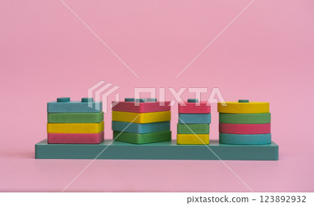 A close-up of a colorful wooden geometric puzzle, designed for Montessori education. The vibrant shapes and natural materials promote learning through play, on a pink background 123892932