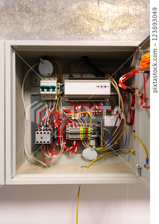 Electrical wiring inside a control box with various connected components in a modern building setting 123893049