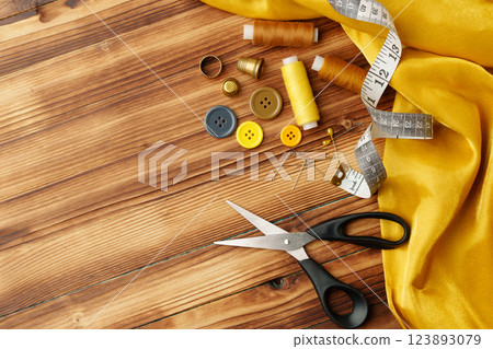 Crafting tools and materials arranged on a wooden table for sewing projects Crafting tools and materials arranged on a wooden table for sewing projects 123893079
