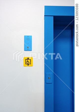 Bright blue elevator entrance features accessibility sign and intercom in a modern building 123893080