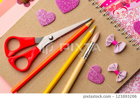 Craft supplies arranged on a tabletop featuring scissors, colored pencils, and decorative heart shapes created for a creative project 123893206