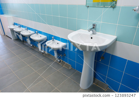 Clean and modern restroom featuring multiple sinks and urinals in a well-maintained facility 123893247