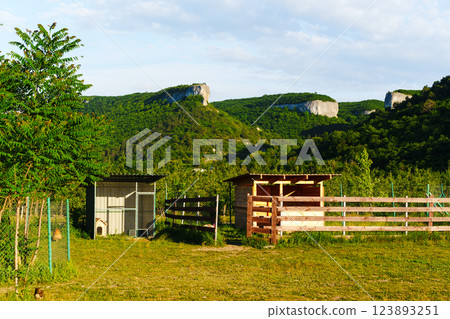 Scenic landscape featuring rustic structures and hills in the background during a sunny day Scenic landscape featuring rustic structures and hills in the background during a sunny day 123893251
