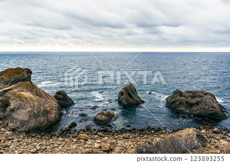 Rocky coastline with ocean waves and cloudy sky creates a serene atmosphere at the seaside 123893255
