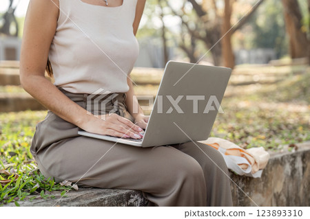 Sustainable lifestyle. Young woman working on her laptop in a park. 123893310