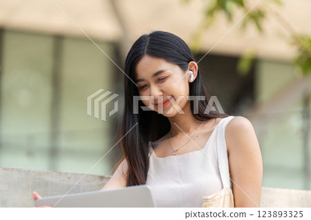 Sustainable lifestyle. Young woman focused on her laptop while enjoying the outdoors. 123893325