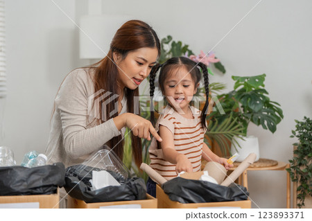 Eco-Consciousness and Family Engagement. A mother and her child engage in recycling at home. 123893371