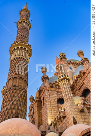 Beautiful architecture of a mosque with intricate details and a towering minaret against a clear blue sky 123893427