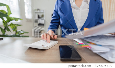 Business and finance. Professional woman calculating taxes with documents and calculator in office setting. 123893429