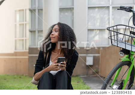 Sustainability and Urban Lifestyle. A young woman reflects while seated next to her green bicycle, embracing eco-friendly transportation. Sustainability and Urban Lifestyle. A young woman reflects while seated next to her green bicycle, embracing eco-friendly transportation. 123893433