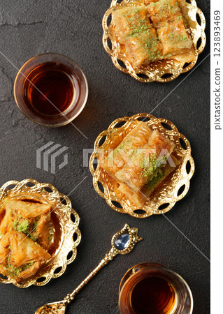 Delightful desserts featuring baklava served with traditional tea on ornate plates in an elegant setting Delightful desserts featuring baklava served with traditional tea on ornate plates in an elegant setting 123893469
