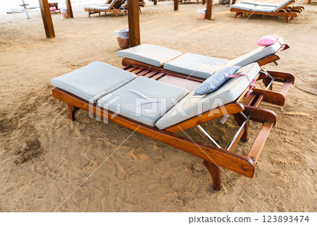 Comfortable lounge chairs on sandy beach, perfect for relaxation and sunbathing near ocean waves in the evening 123893474