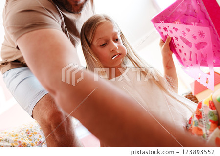 A young girl is looking at a pink stencil, her father is behind her A young girl is looking at a pink stencil, her father is behind her 123893552