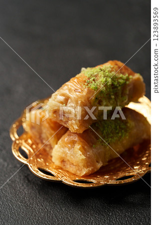 Delicious baklava dessert with pistachio topping served on a decorative plate 123893569