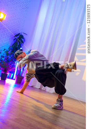 A dancer performs a breakdancing move in a studio with colorful lighting A dancer performs a breakdancing move in a studio with colorful lighting 123893575