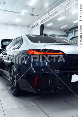 Modern black sedan parked in a well-lit auto showroom during the day 123893590