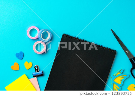 Creative workspace with colorful stationery and supplies arranged on a bright blue background 123893735