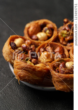 Delicious assortment of crispy pastry filled with nuts presented in a charming bowl on a dark surface Delicious assortment of crispy pastry filled with nuts presented in a charming bowl on a dark surface 123893751