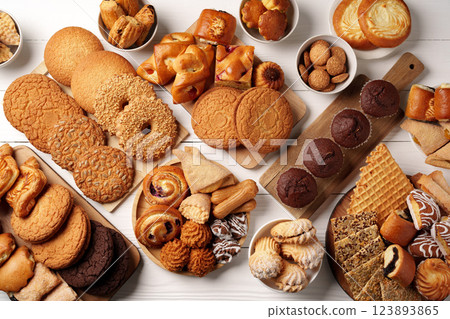Variety of baked goods displayed on wooden surfaces, including cookies, pastries, and sweet treats for a delightful gathering Variety of baked goods displayed on wooden surfaces, including cookies, pastries, and sweet treats for a delightful gathering 123893865