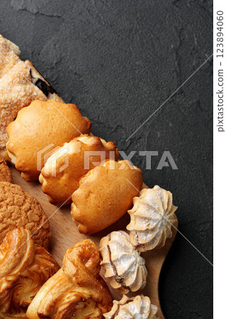 Freshly baked assortment of delicious cookies and pastries on a wooden platter with a dark textured background Freshly baked assortment of delicious cookies and pastries on a wooden platter with a dark textured background 123894060