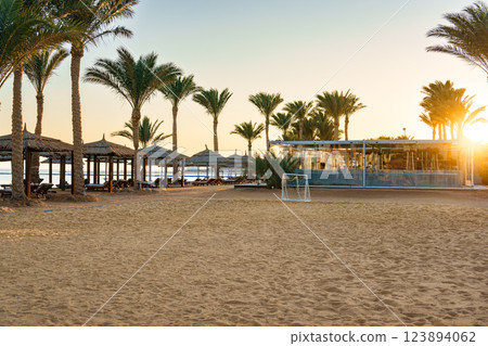 Sunset at a tranquil beach in a coastal resort with palm trees and a soccer goal on the sand Sunset at a tranquil beach in a coastal resort with palm trees and a soccer goal on the sand 123894062