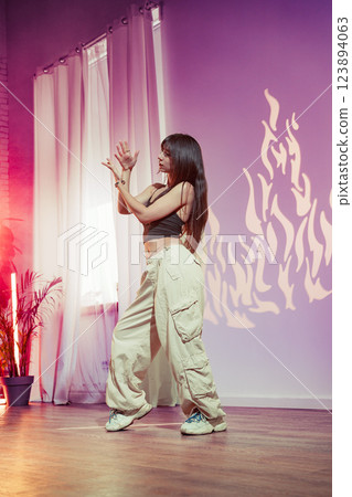 Dancer performs contemporary routine in studio with warm lighting and dynamic shadow patterns in the background 123894063
