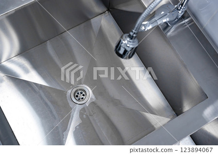 Stainless steel sink with water droplets reflecting light in a modern kitchen setting Stainless steel sink with water droplets reflecting light in a modern kitchen setting 123894067