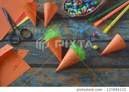 Carrots gift Bag for candies. DIY paper craft with your own hands together with children. Easter treat box. Art project for kids. Step by step guide. Carrots gift Bag for candies. DIY paper craft with your own hands together with children. Easter treat box. Art project for kids. Step by step guide. 123894132