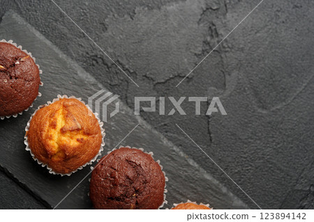 Freshly baked muffins displayed on a dark slate surface, showcasing a variety of flavors and textures inviting a delicious treat Freshly baked muffins displayed on a dark slate surface, showcasing a variety of flavors and textures inviting a delicious treat 123894142