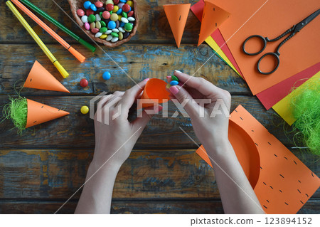 Carrots gift Bag for candies. DIY paper craft with your own hands together with children. Easter treat box. Art project for kids. Step by step guide. Carrots gift Bag for candies. DIY paper craft with your own hands together with children. Easter treat box. Art project for kids. Step by step guide. 123894152