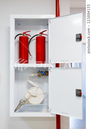 Storage cabinet containing fire extinguishers and hoses in a modern building setting 123894155
