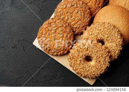 Assorted cookies displayed on a wooden platter with a dark background Assorted cookies displayed on a wooden platter with a dark background 123894156
