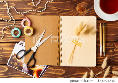 Creative workspace showcasing tools for crafting and journaling with a cup of tea nearby 123894250