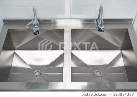 Stainless steel double sink in a kitchen setting with modern fixtures 123894337
