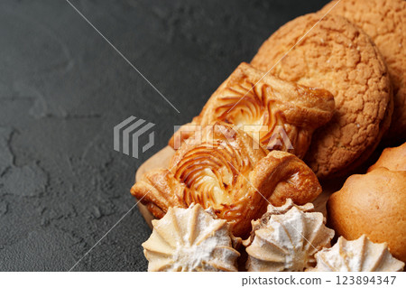 Delicious variety of cookies arranged on a dark wooden surface ready for tasting during an afternoon gathering Delicious variety of cookies arranged on a dark wooden surface ready for tasting during an afternoon gathering 123894347