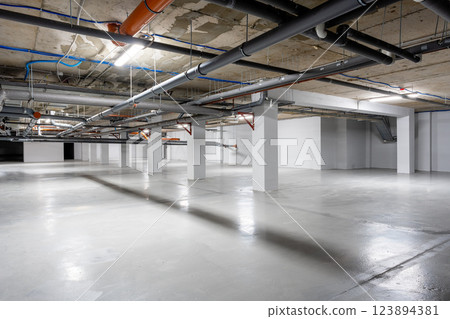 Empty underground parking lot with industrial features and bright lights during the day Empty underground parking lot with industrial features and bright lights during the day 123894381